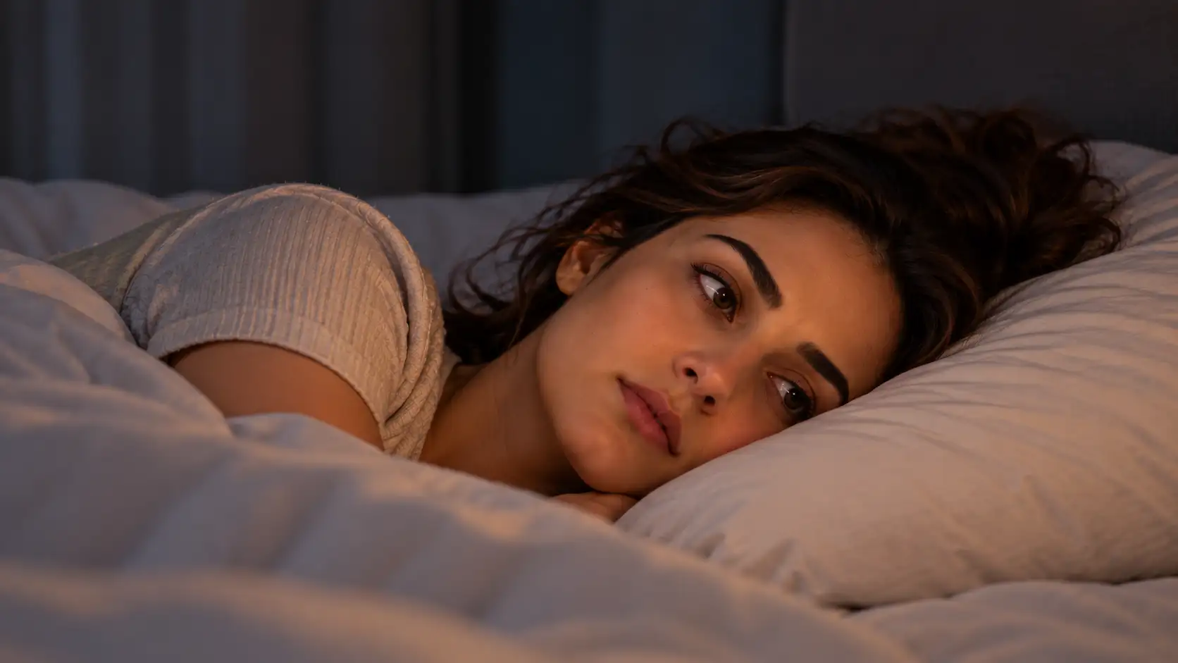 Woman lying awake in bed, eyes open