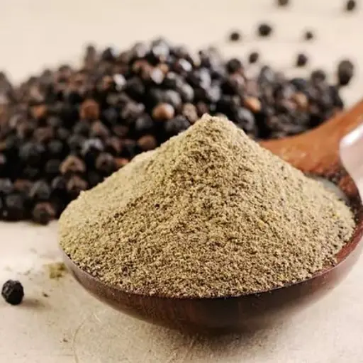Ground black pepper on a wooden spoon with whole peppercorns