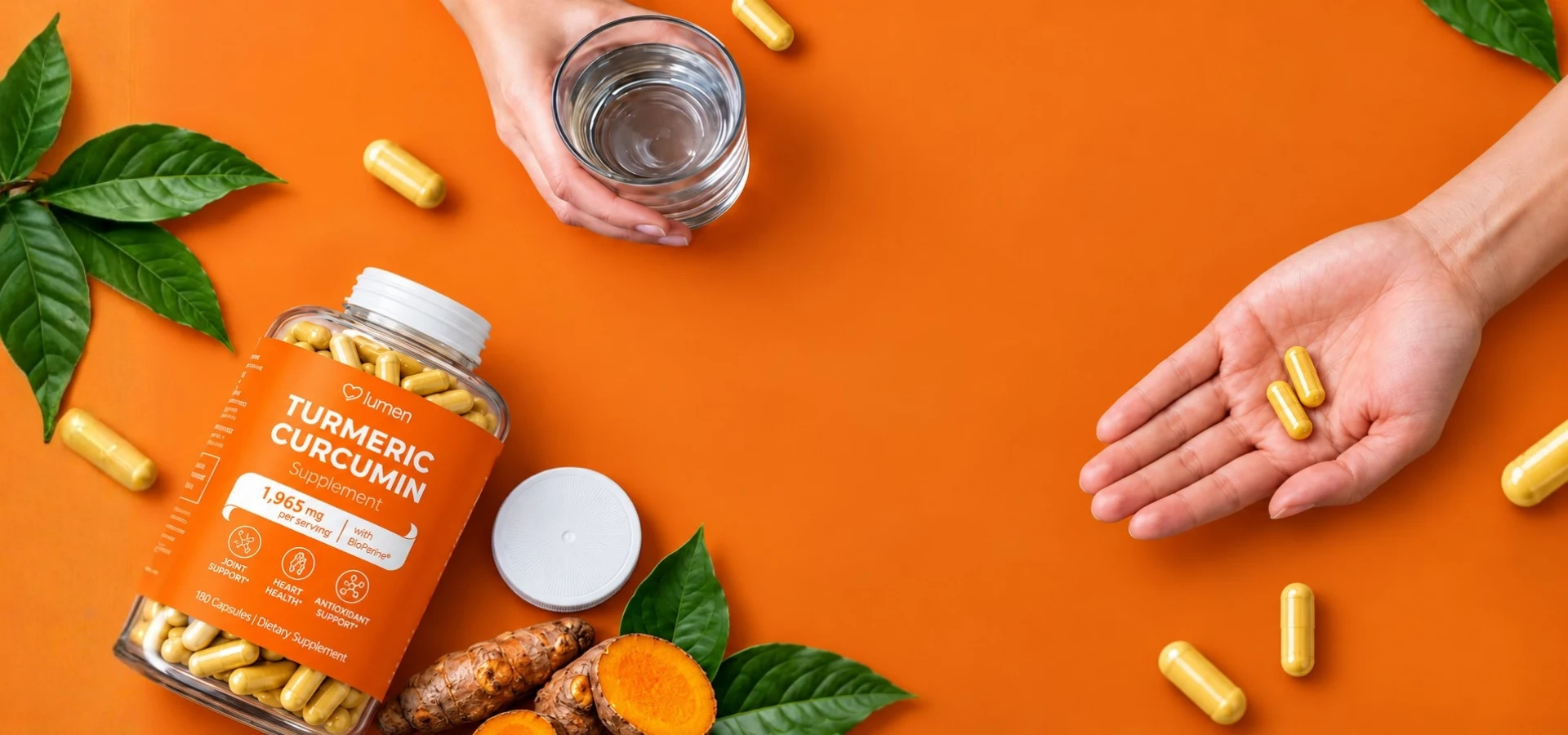 Lumen Turmeric Curcumin bottle with capsules, a glass of water, turmeric root and leaves on an orange background